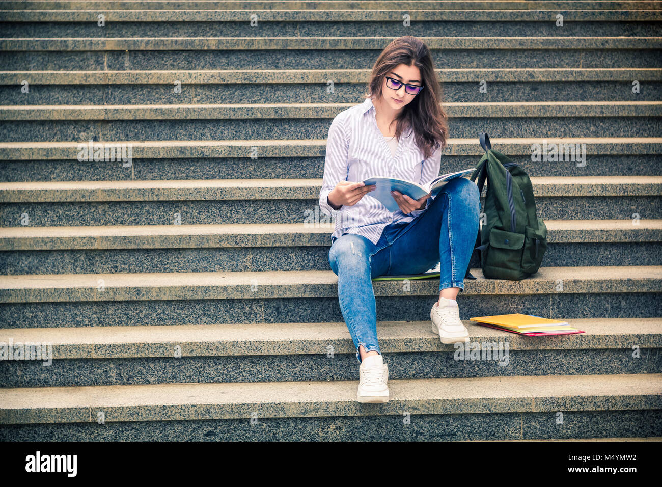 Schöne Mädchen, ein Student in der Brille liest ein Buch auf der Treppe. Allgemeine und berufliche Bildung. Indische College Stockfoto