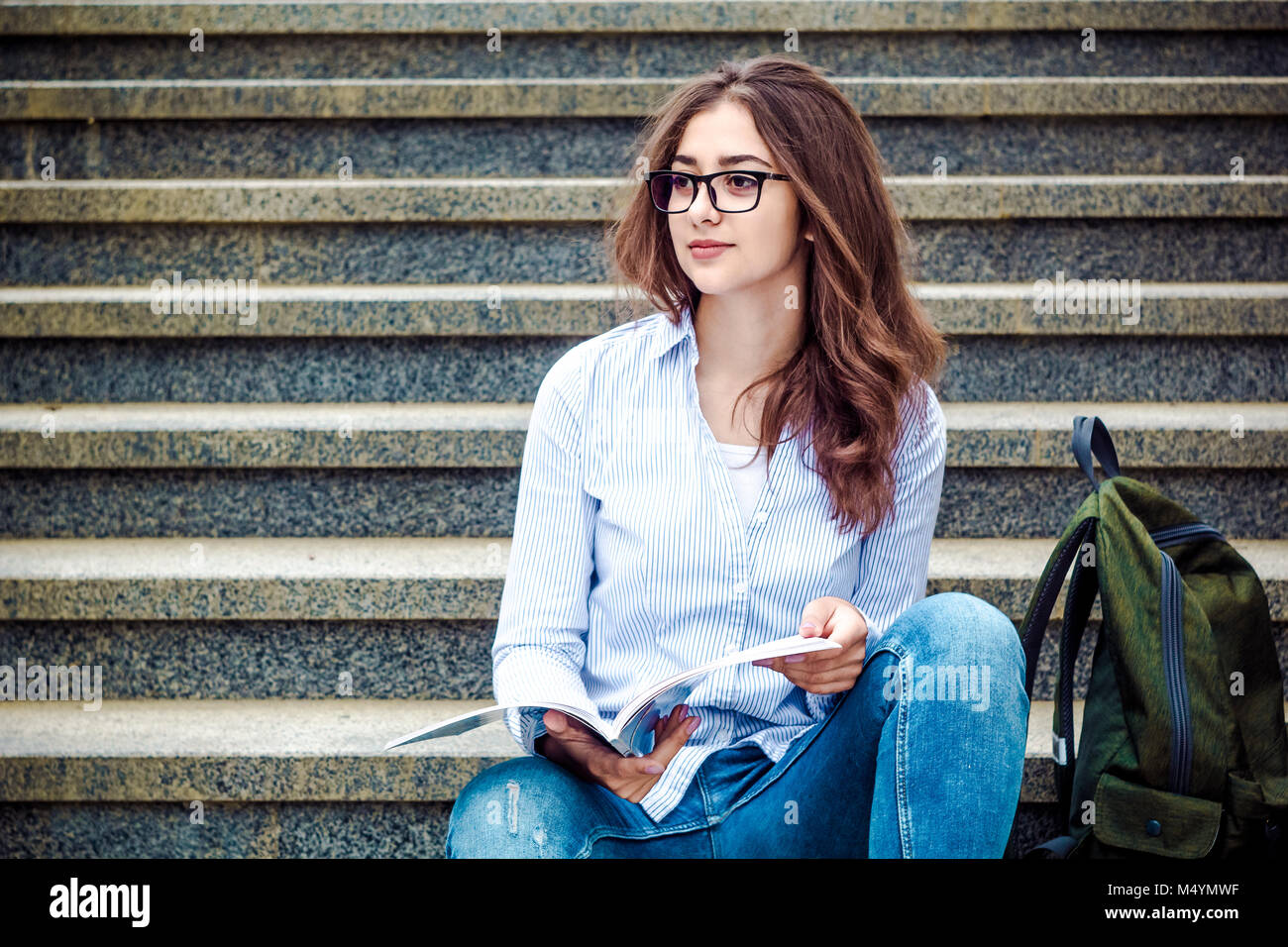Schöne Mädchen, ein Student in der Brille liest ein Buch auf der Treppe. Allgemeine und berufliche Bildung. Indische College Stockfoto