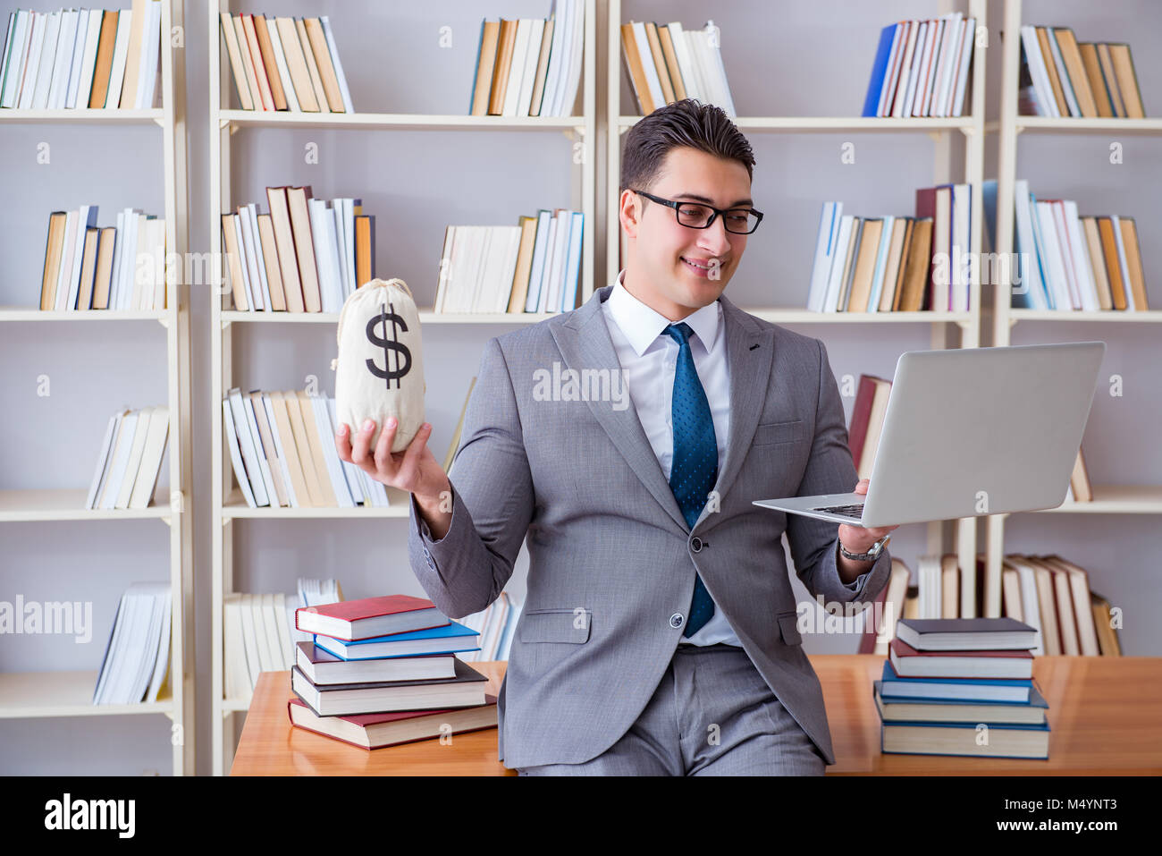 Geschäftsmann in Bibliothek mit meschotschek Geld und laptop Stockfoto