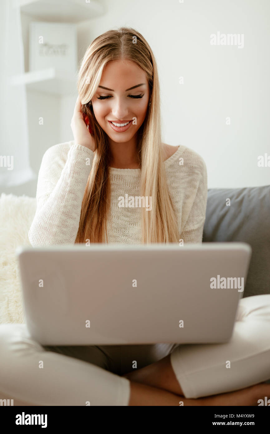 Schöne junge lächelnde Frau am Haus entspannen und Surfen im Netz auf einem Laptop. Stockfoto
