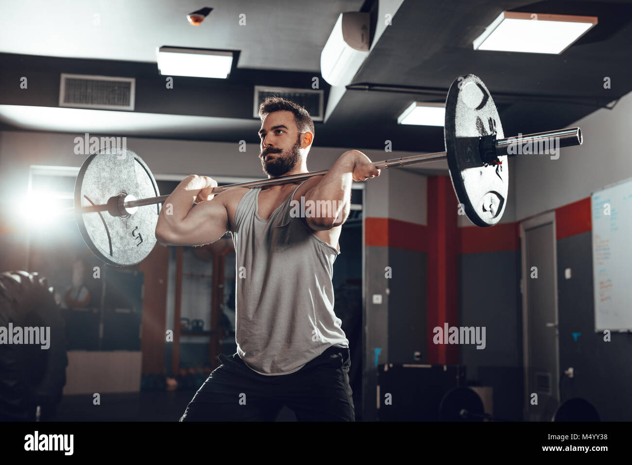Junge muskulöse Mann Anheben einer Langhantel im Fitnessstudio. Stockfoto