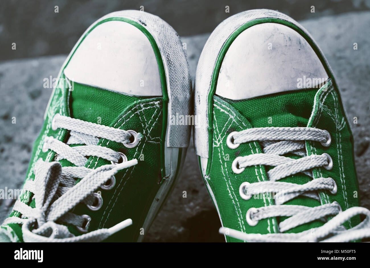Füße in schmutzigen grünen Turnschuhe und Jeans im Freien. Der erste Schritt. Stockfoto