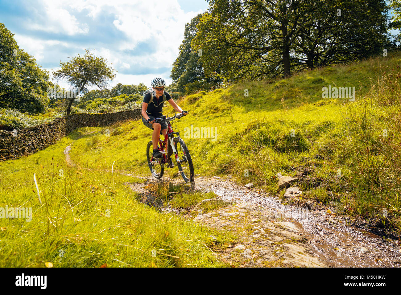 Weibliche Mountainbiker auf der Strecke in der Nähe Winster im englischen Lake District Stockfoto