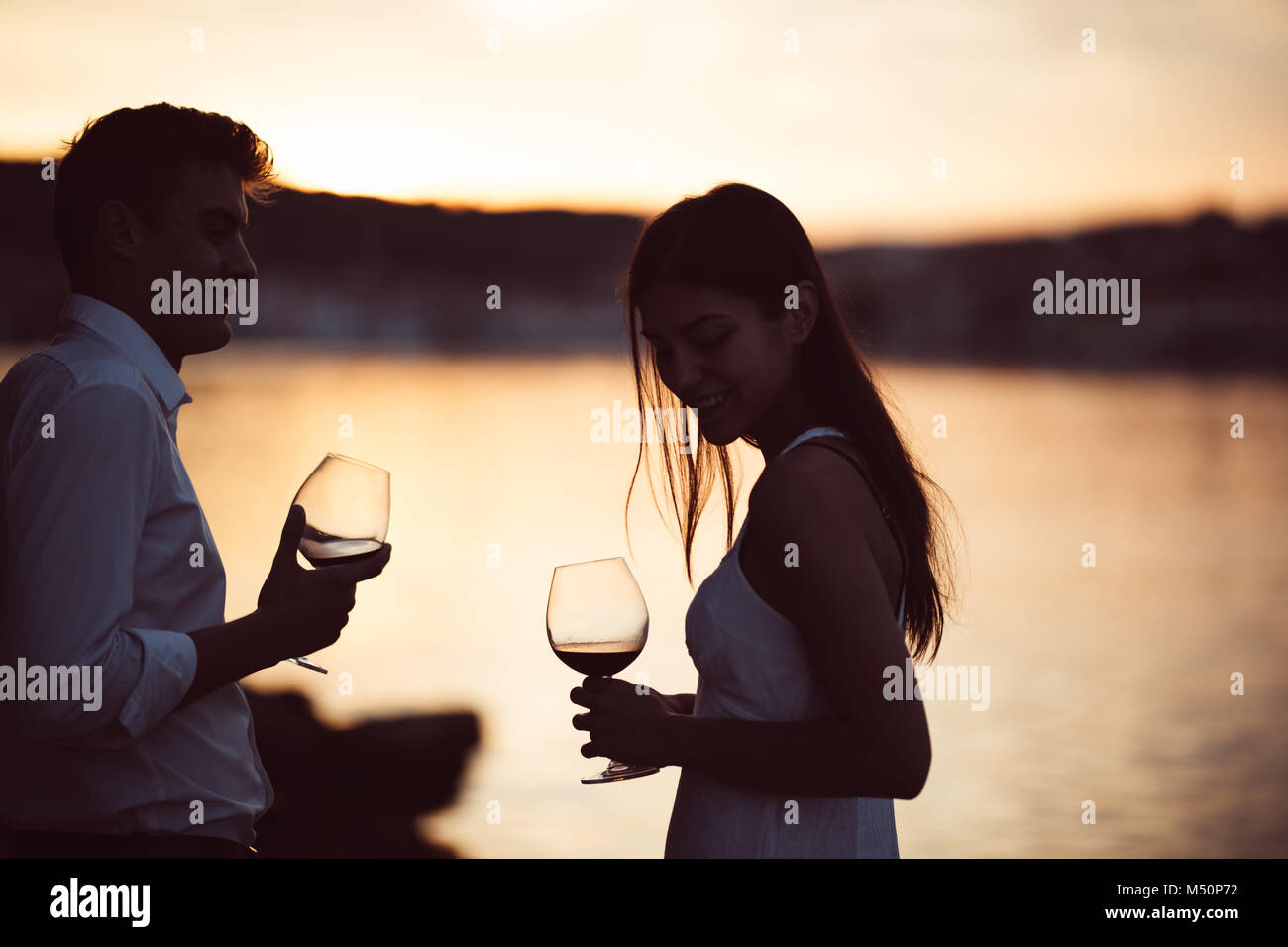 Zwei junge Menschen bei einem Glas Rotwein den Sonnenuntergang am Meer. Gesunde Glas od hausgemachten Rotwein, mediterrane Kultur. warmem Klima, Meere Stockfoto