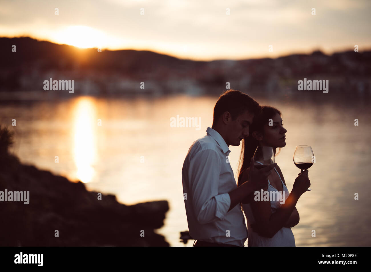 Zwei junge Menschen bei einem Glas Rotwein den Sonnenuntergang am Meer. Gesunde Glas od hausgemachten Rotwein, mediterrane Kultur. warmem Klima, Meere Stockfoto
