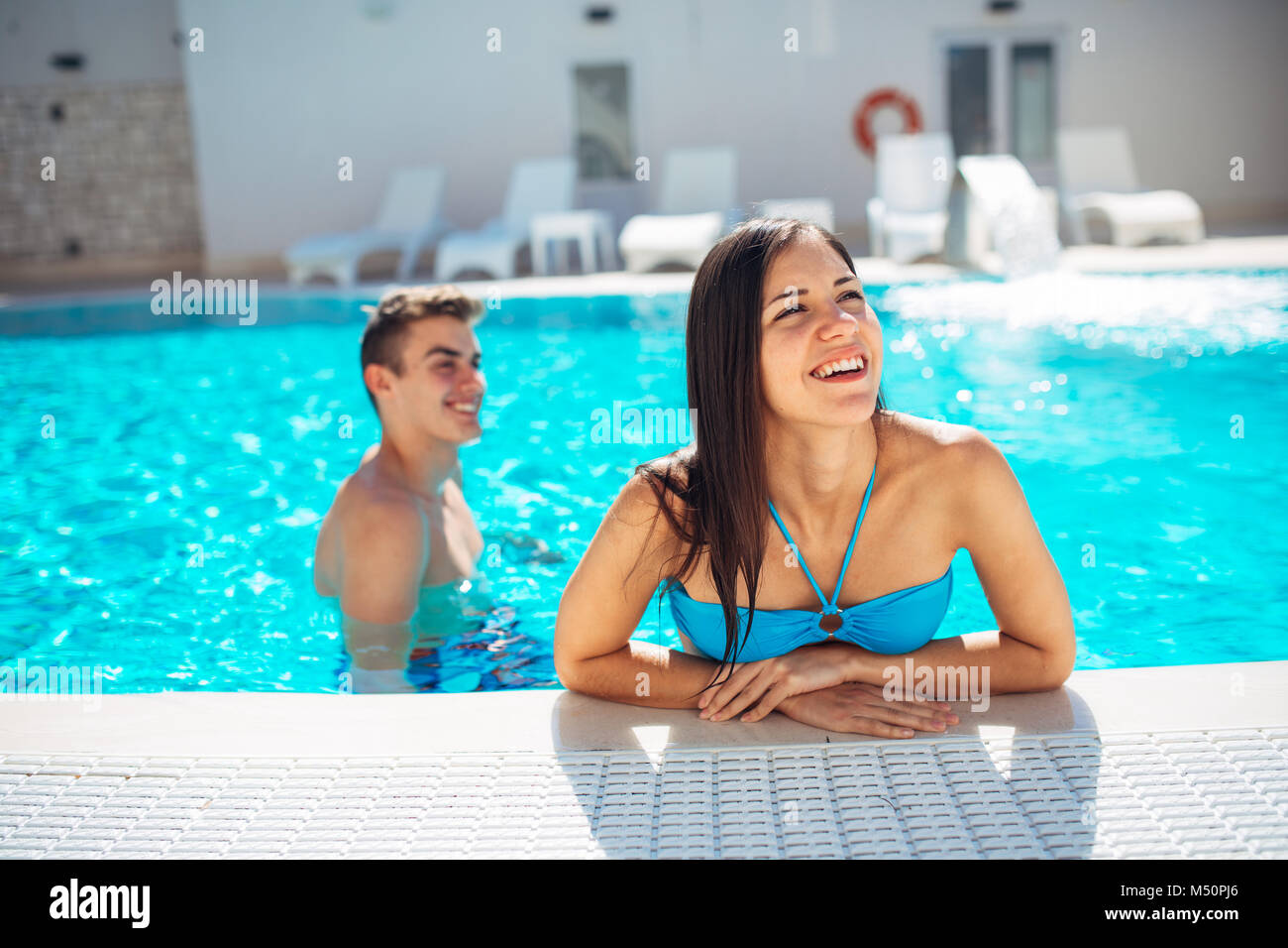 Lächelnd fröhliche Frau schwimmen in einem klaren Pool an einem sonnigen Tag. viel Spaß im Urlaub Pool Party. Freundliche Hündin genießen Sie erholsamen Urlaub. Summe Stockfoto