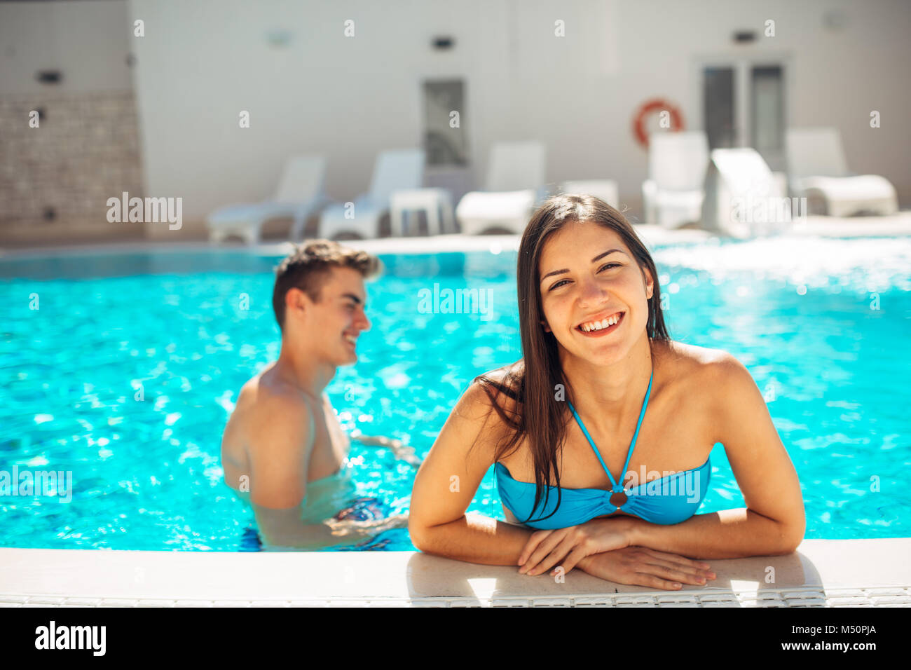 Lächelnd fröhliche Frau schwimmen in einem klaren Pool an einem sonnigen Tag. viel Spaß im Urlaub Pool Party. Freundliche Hündin genießen Sie erholsamen Urlaub. Summe Stockfoto