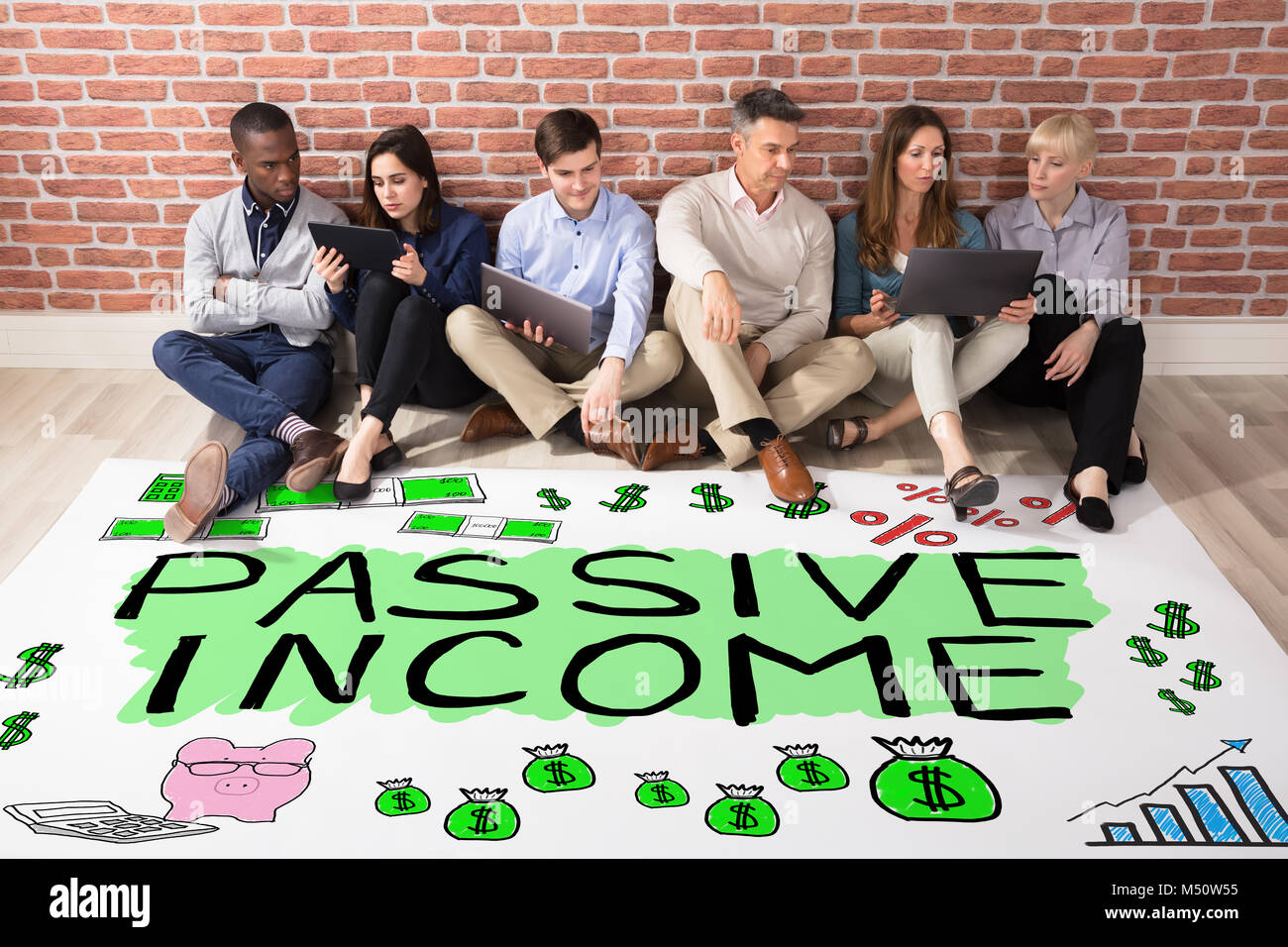 Gruppe von Menschen, die auf der Suche am passiven Einkommen Text auf dem Boden Stockfoto
