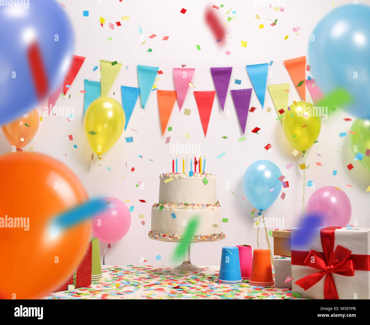 Geburtstag Kuchen mit brennenden Kerzen gegen eine Wand mit Dekoration Fahnen Stockfoto