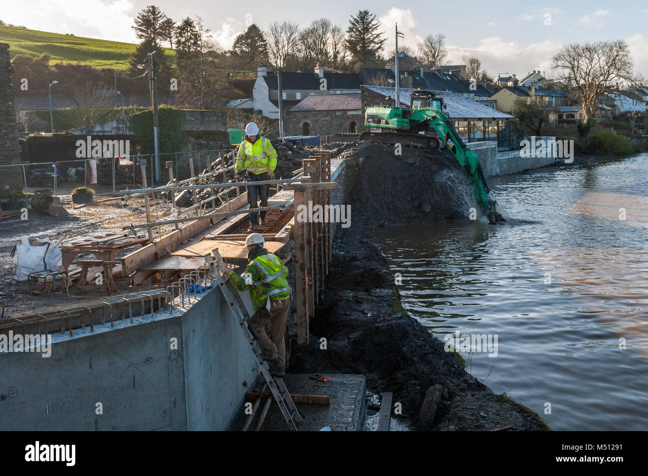 Arbeiter und ein Caterpillar 320D Bagger arbeiten an Skibbereen's Hochwasserschutz, County Cork, Irland. Stockfoto