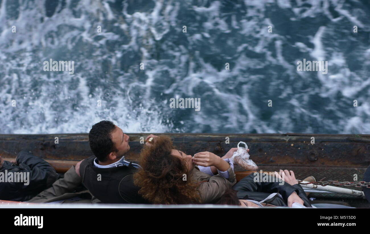 Ein Mädchen mit lockigem Haar essen Brot (simit) auf der Überfahrt mit der Fähre die Donau in Istanbul. Stockfoto