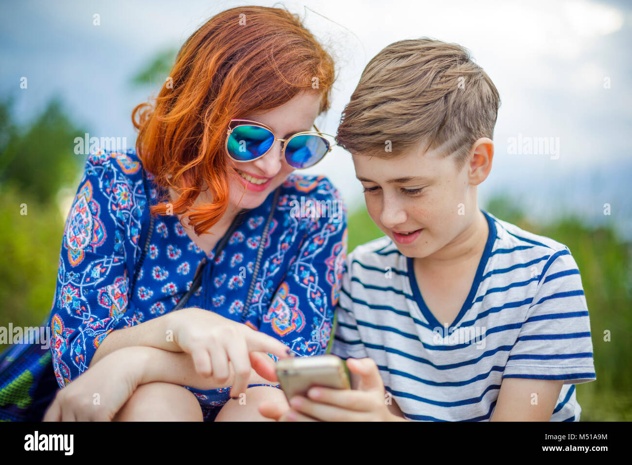 Glückliche Mutter mit Sohn und Smartphone im Park Stockfoto