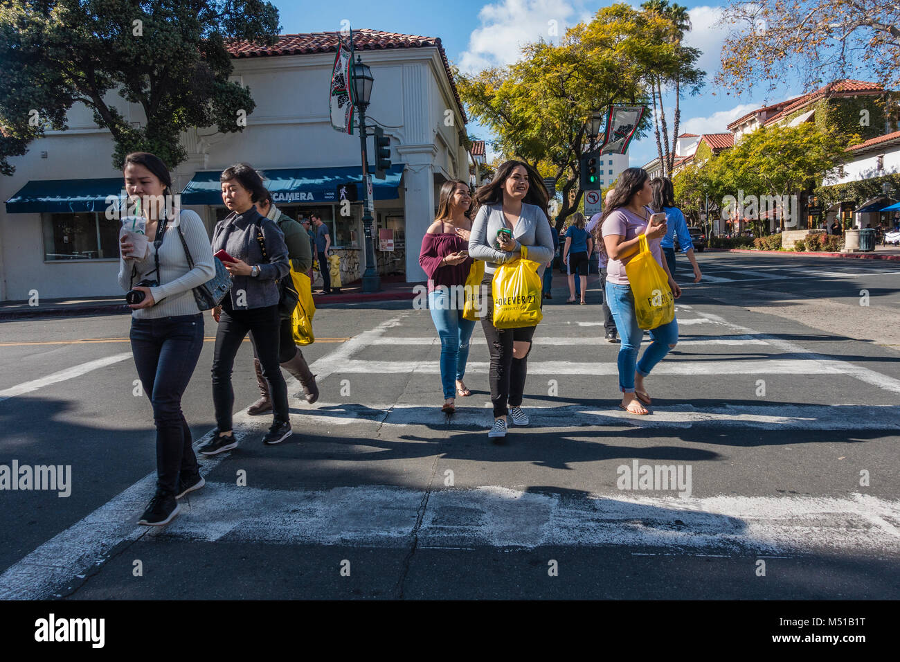 Junge hispanischen Frauen Shopper überqueren Sie die Straße ihre Einkäufe in Einkaufstaschen. Stockfoto
