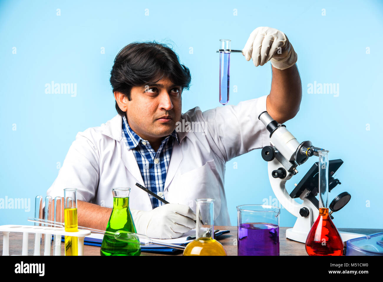 Asiatische/Indische männliche Wissenschaftler oder Arzt oder Wissenschaft Schüler experimentieren mit Mikroskop und Chemikalien, Laptop und Smartphone in einem Labor Stockfoto