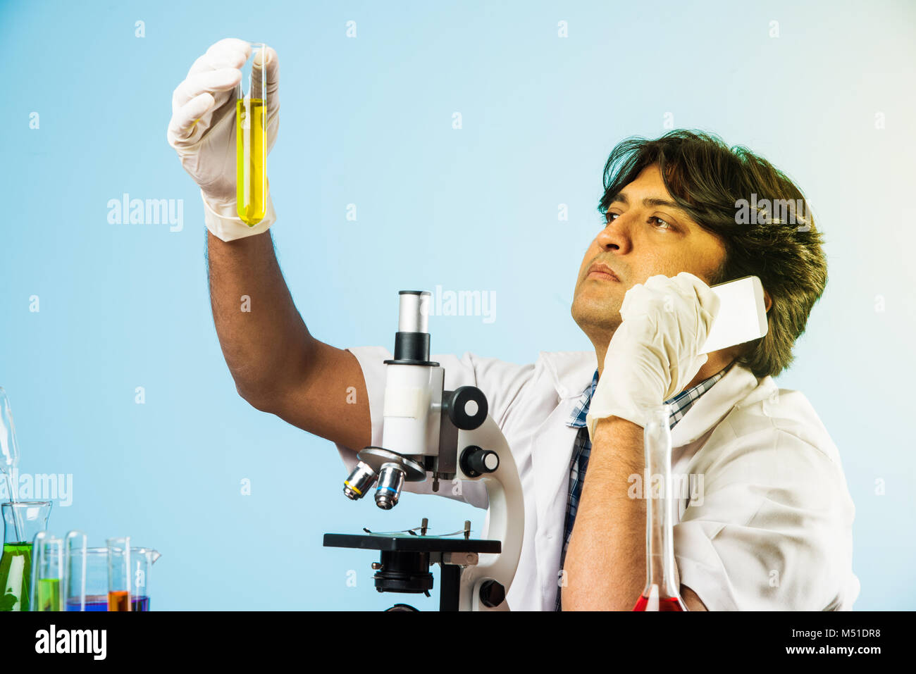 Asiatische/Indische männliche Wissenschaftler oder Arzt oder Wissenschaft Schüler experimentieren mit Mikroskop und Chemikalien, Laptop und Smartphone in einem Labor Stockfoto