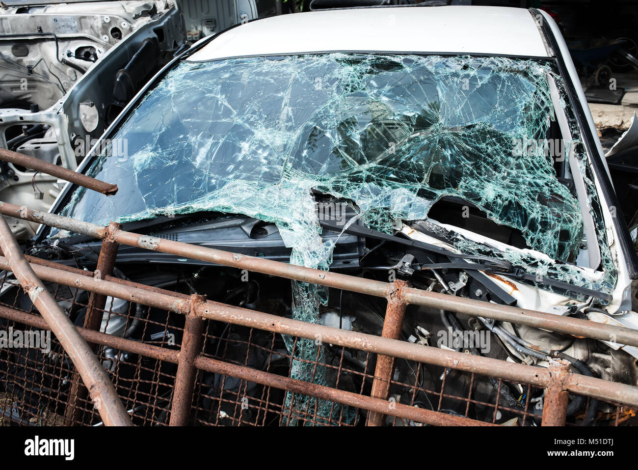 Die crash Unfall Auto whit gebrochene Frontscheibe Spiegel an den Papierkorb garage Foto mit niedriger Beleuchtung im Freien. Stockfoto