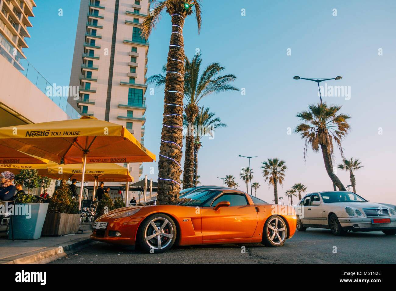 Ein metallisch orangefarbener Chevrolet Corvette C6 LS3 steht an einem sonnigen Nachmittag vor einem Café in Beirut, Libanon, parkt Stockfoto