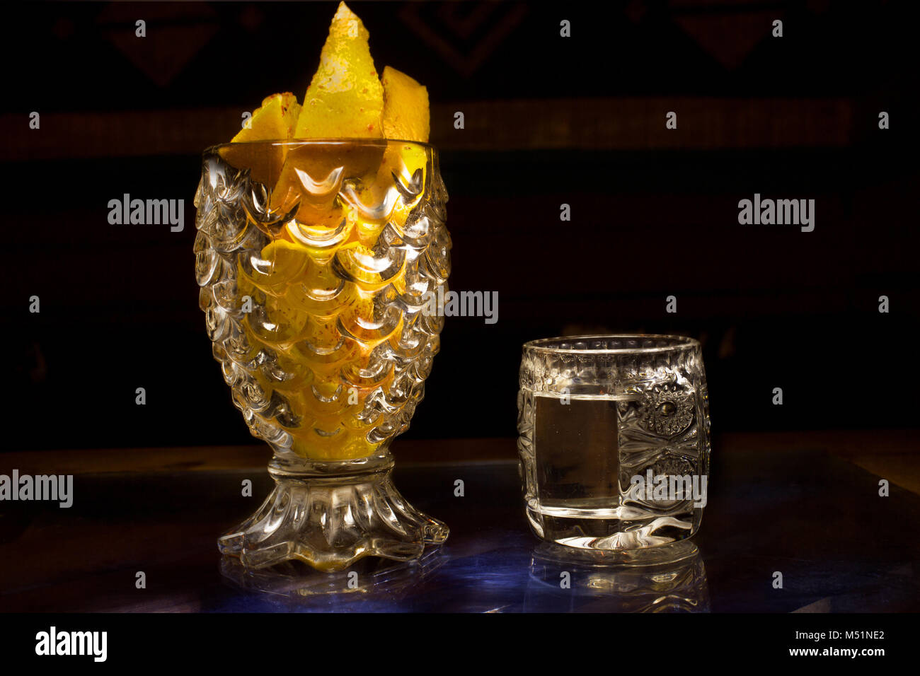 Mexikanische Mezcal in einem Glas neben Crystal Becher mit Schichten von Orangen Stockfoto