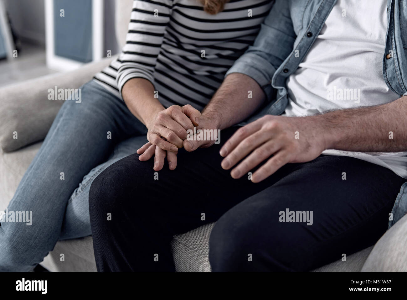 Liebevolle Frau, die eine Hand auf ihren Ehemann während der Sitzung mit ihm Stockfoto