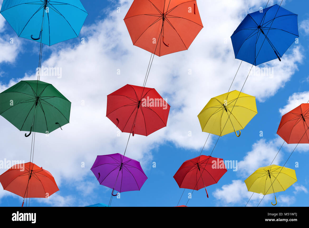 Bunte Schirme hängen hoch über dem Boden Stockfoto