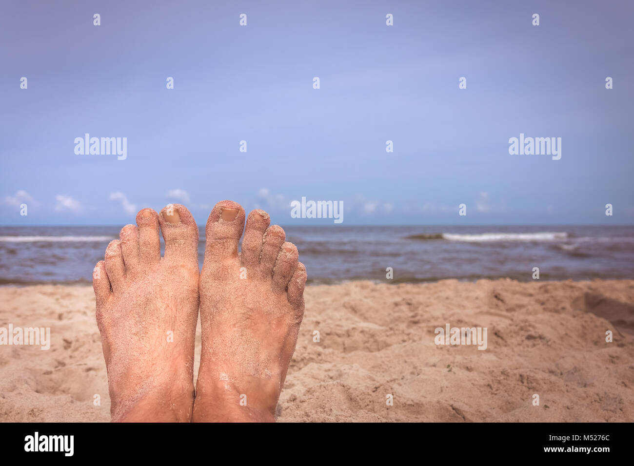 Mans Füßen am Strand Stockfoto
