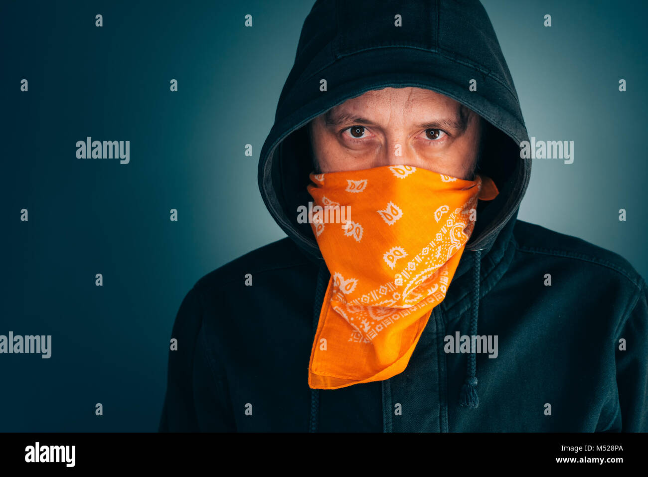 Portrait von maskierten Kriminellen männliche Person an der Kamera schaut. Erwachsener Mann mit Kapuze und Schal über Gesicht als Bandit oder Gangmitglied. Stockfoto