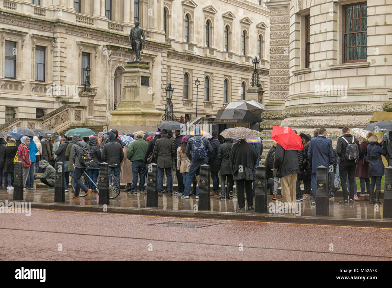 LONDON, UK, 10. Februar 2018: Die Menschen in der Linie im Regen mit Sonnenschirme für den Eingang von Churchill War Rooms in London warten. Stockfoto