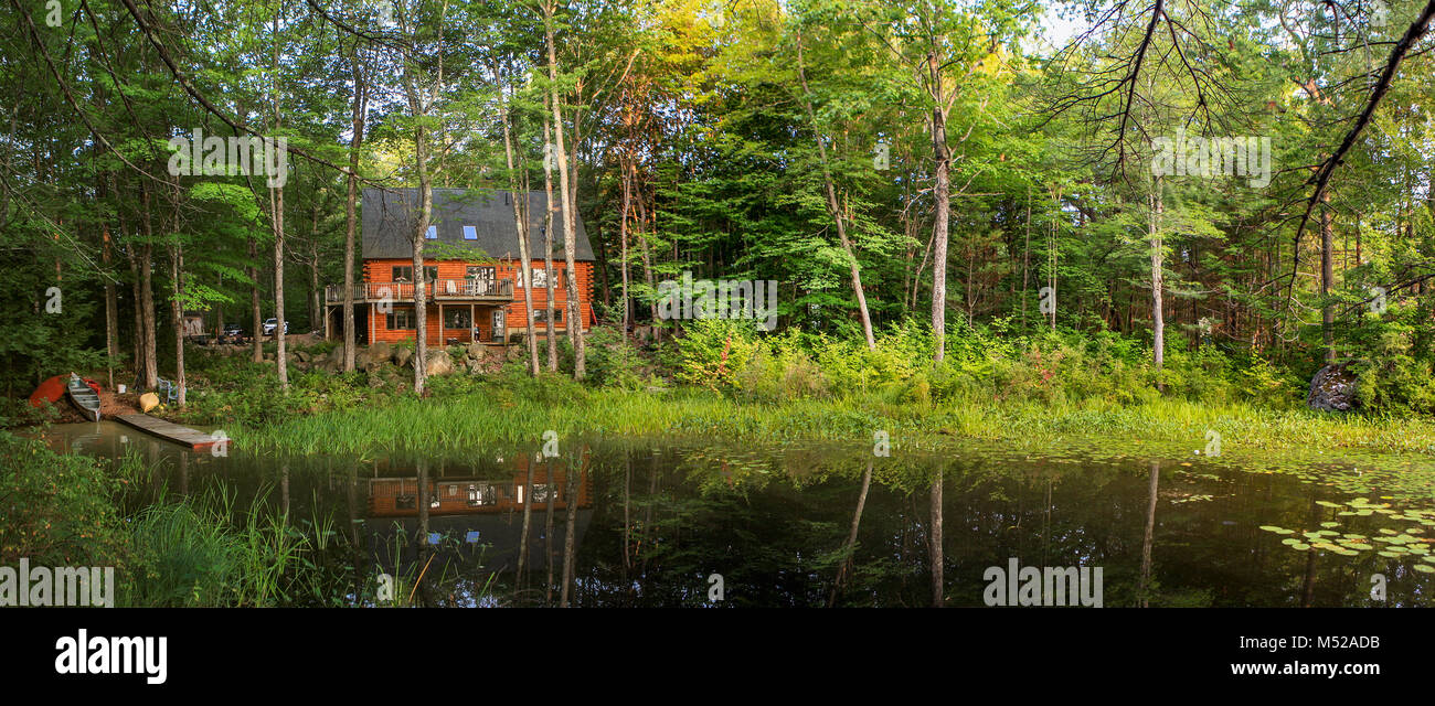 Morgen Sonnenschein badet ein modernes anmelden Urlaub zu Hause mit einem Teich, Dock und Kanus in idyllischer Lage umgeben von Wäldern, Frieden und Ruhe umgeben. Stockfoto