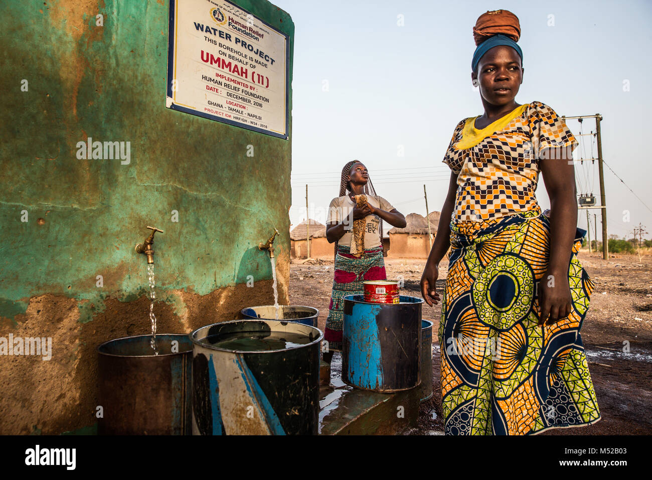 Zwei Frauen stehen durch ein gut in dem abgelegenen Dorf Nepilsi, 30 km außerhalb von Tamale im Norden Ghanas. Die menschliche Befreiung Stiftung begann die Arbeit an einem Gut mit frischem Wasser für das Dorf vor zwei Jahren, besuchten wir die positiven Auswirkungen auf die Gemeinschaft hat. Diese Bereiche des Ghana sind so abgelegen und der Armut sind einige der niedrigsten der Welt. Stockfoto