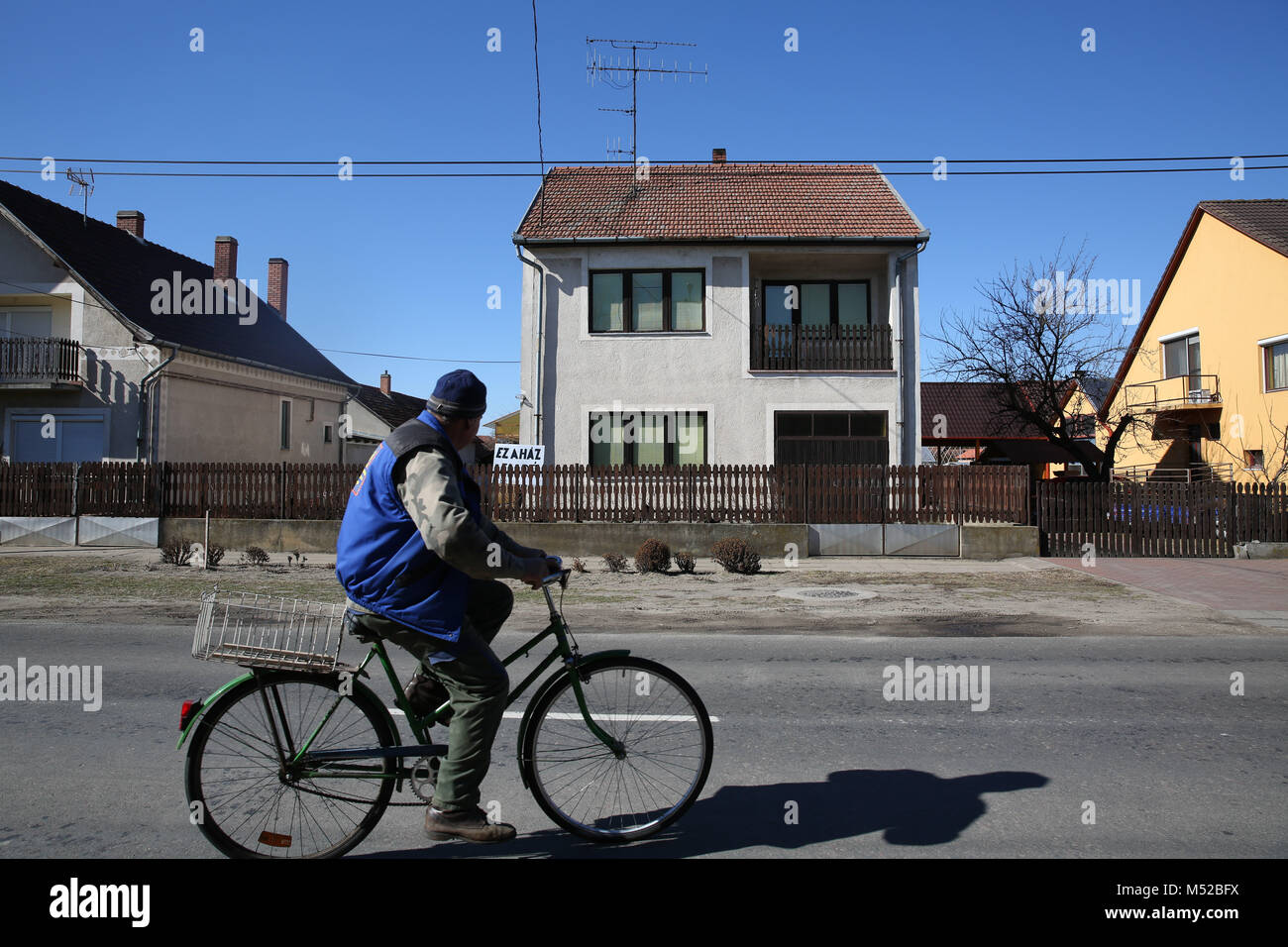 Ein Mann Zyklen hinter einem Haus in Asotthalom, der ungarischen Stadt, deren weit rechts Bürgermeister kurz verboten "homosexuelle Propaganda" und der Ruf zum Gebet. Stockfoto