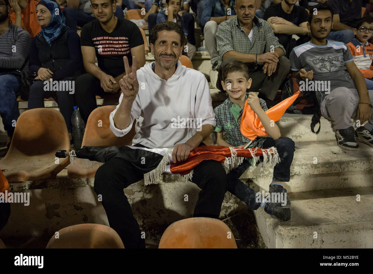 Vater und Sohn beobachten Sie die syrischen Fußball WM-Finale, 2017, von der Tribüne aus. Viele Eltern sagten, daß sie noch zu haben Angst, ihre Kinder in die Spiele zu bringen. Die syrischen Fußball WM-Finale wurde zwischen Al-Wahda und Al-Karamah Fußball-Mannschaften gespielt. Trotz des anhaltenden Konflikts in der vom Krieg zerrissenen Land, in Syrien, dem syrischen Fußball Cup fand in der Hauptstadt Damaskus, die unter der syrischen Regierung Steuerung ist mit vielen einheimischen Fußball-Fans das Match besucht. Stockfoto