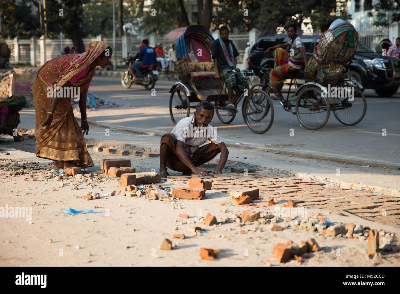 Ein Mann und seine Frau arbeiten hart und ebnet den Weg in der Nähe der Park der Unabhängigkeit. Dhaka, die Hauptstadt Bangladeschs liegt am Ostufer des Buriganga River im Herzen der Bengal delta. Die Stadt ist ein Mikrokosmos des ganzen Landes, mit den verschiedenen religiösen und ethnischen Gemeinschaften. Dhaka ist die wirtschaftliche, kulturelle und politische Zentrum von Bangladesch und ist ein bedeutender Finanzplatz in Südasien. Es ist eines der am dichtesten besiedelten Städte der Welt mit einer Bevölkerung von 18.89 Millionen Menschen im Großraum Dhaka. Stockfoto