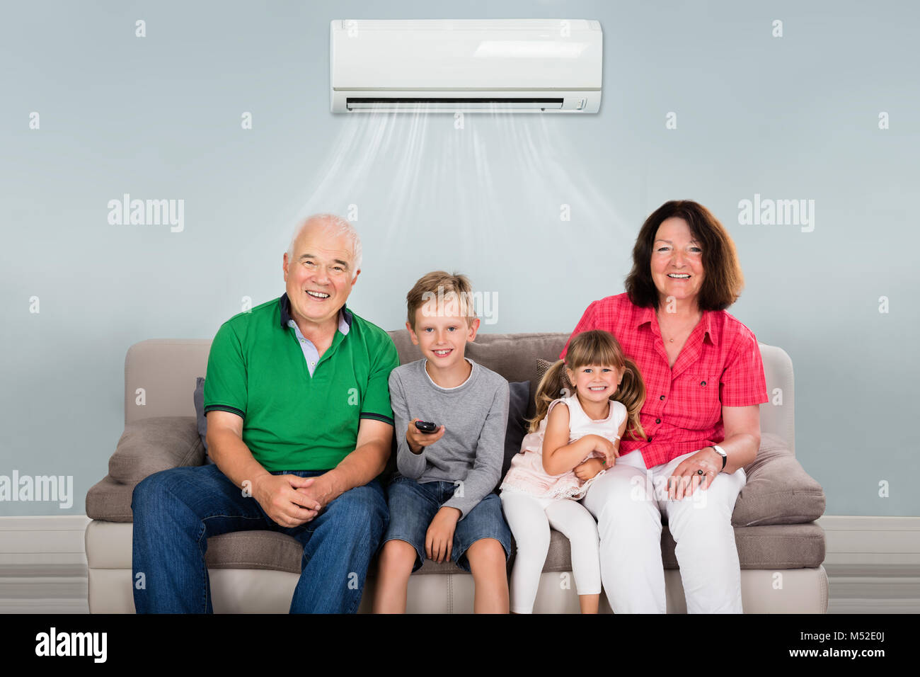 Happy Multi Generation Familie mit zwei Kindern Fernsehen unter Klimaanlage zu Hause Stockfoto