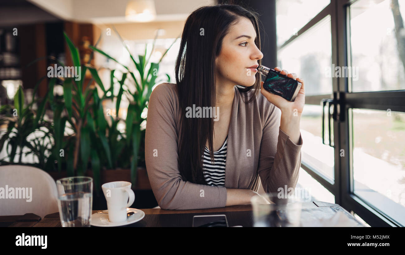 Junge Frau mit elektronische Zigarette an öffentlichen Orten zu rauchen. Rauchen Einschränkung, Rauchen verbieten. Mit vaping Gerät mit gewürzte Flüssigkeit. E-Saft vapin Stockfoto