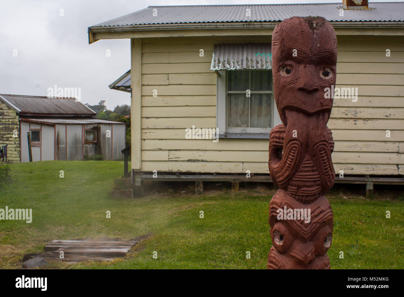 Lebenden Maori Dorf, Maori Holzschnitzerei Skulptur und Häuser im Hintergrund Stockfoto