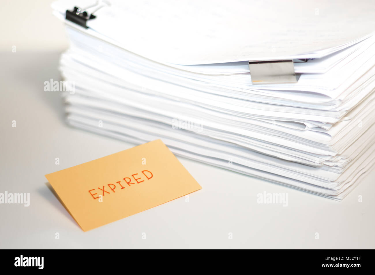 Abgelaufen; Stapel von Dokumenten auf weißem Schreibtisch und Hintergrund. Stockfoto