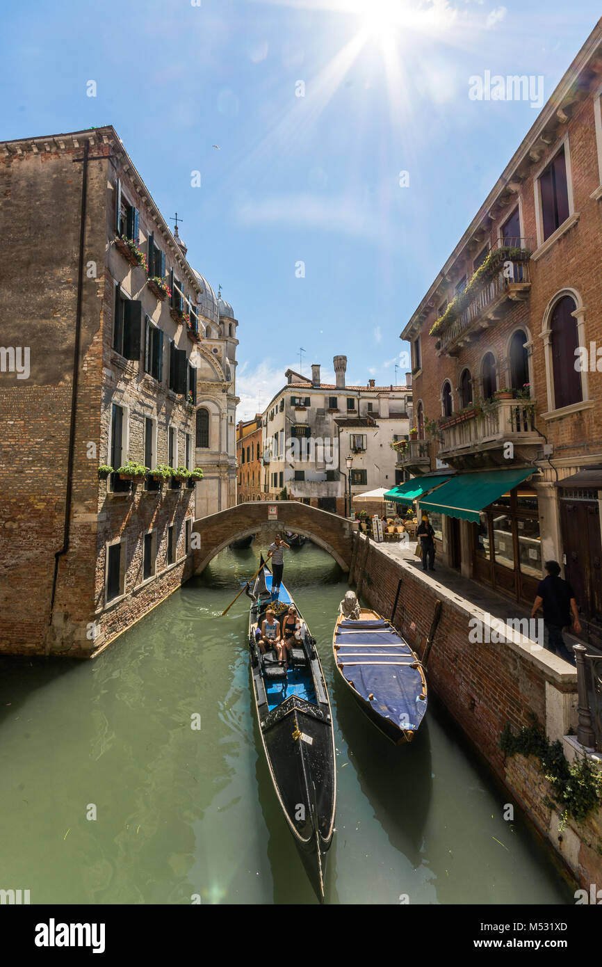 Die wunderschönen Venezianer Stadt Kanal Routen und Gondelfahrten, die Sun Flair in der Ecke der Altstadt Gebäude vor. Stockfoto