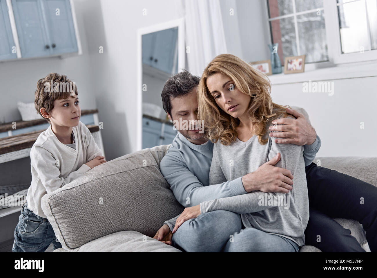 Friedliche Eltern umarmen und Ihre neugierigen Sohn stand in der Nähe und Suchen Stockfoto