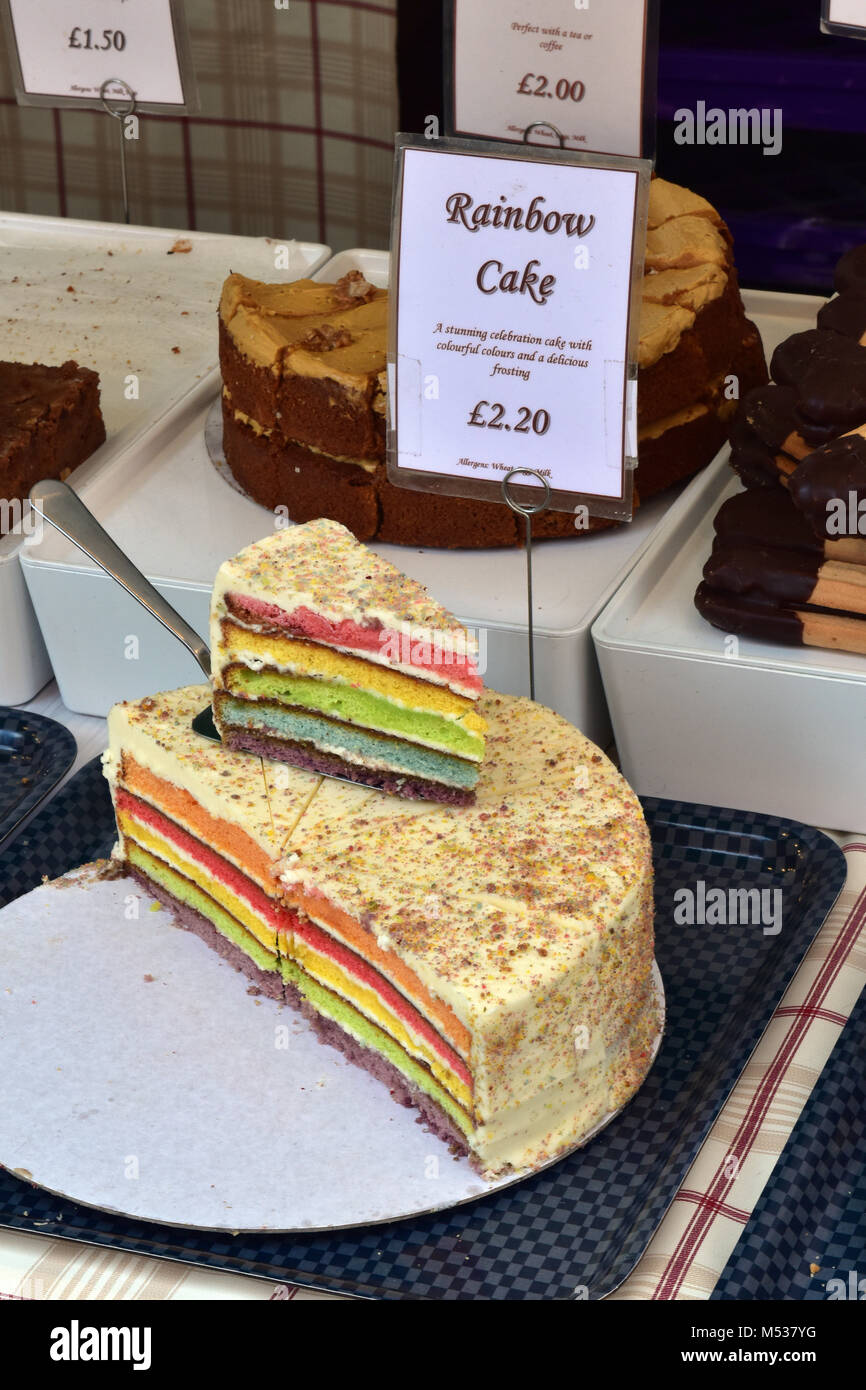 Eine bunte backen Regenbogen Kuchenscheiben zum Verkauf auf einem Marktstand verkaufen Köstlichkeiten und süßen Kuchen und Bäcker. Süße Backwaren zum Verkauf an. Stockfoto