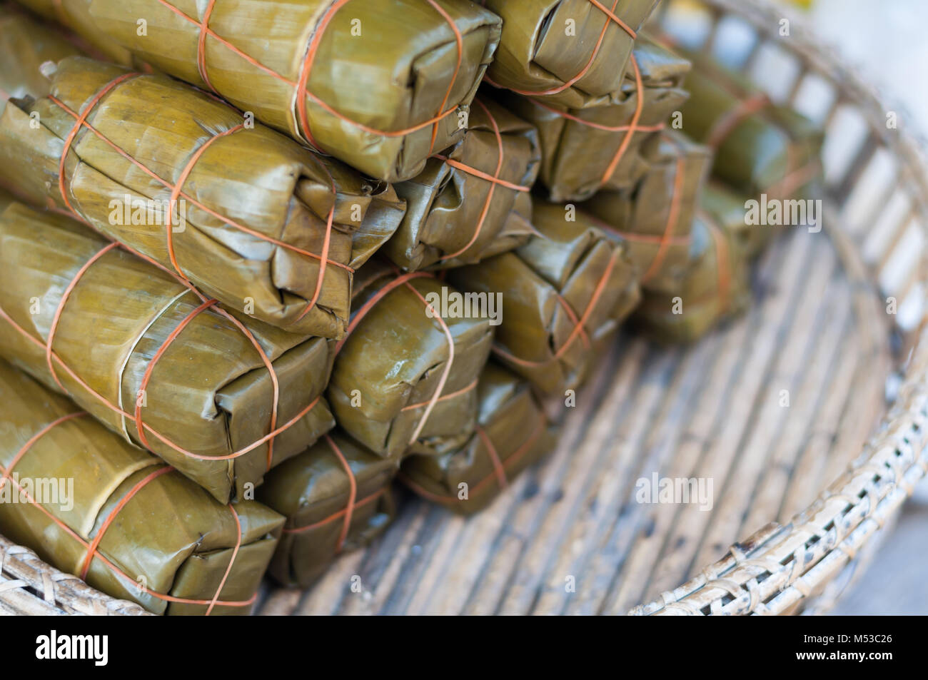 Close up Bananen mit klebrigem Reis pack auf Holz Korb rattan Markt, Khao Tom Schlamm, blur Hintergrund Stockfoto