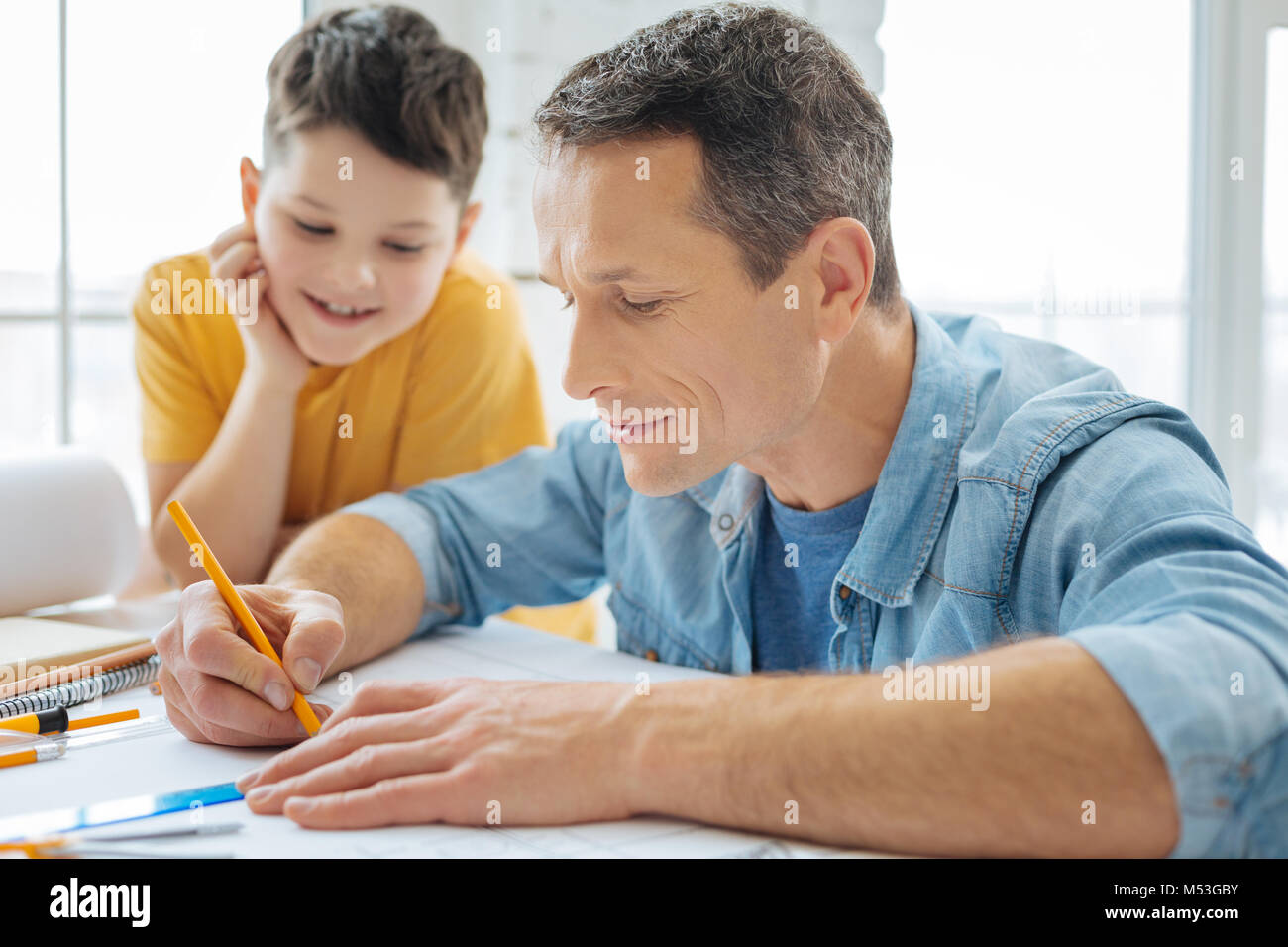 Schöner mann Zeichnung Blaupause, während sein Sohn beobachten Stockfoto