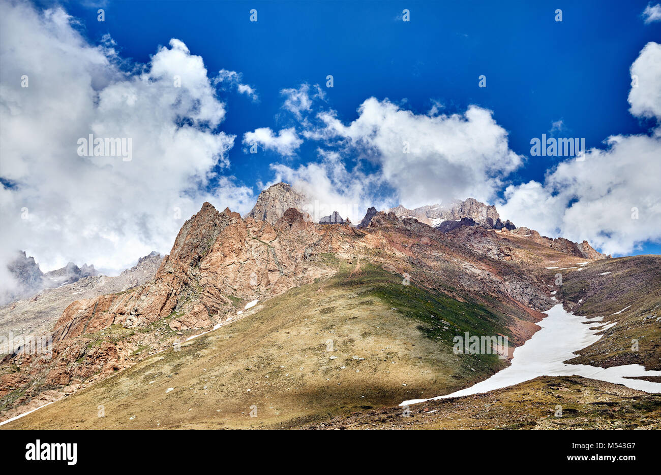 Landschaft der schneebedeckten Berge mit bewölktem Himmel Hintergrund Stockfoto