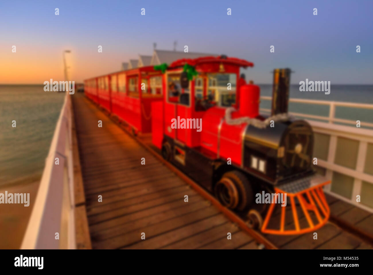 Defokussiertem Hintergrund mit malerischer Vintage rot Dampflok auf hölzernen Steg. Iconic in Busselton, Western Australia, an der blauen Stunde. Absichtlich verschwommene Postproduktion für bokeh Wirkung. Platz kopieren Stockfoto