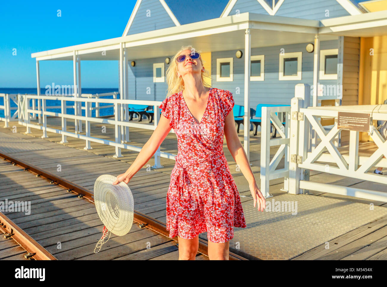 Sorglos blonde Frau genießt den Sonnenuntergang Licht auf berühmten busselton Holzsteg in Busselton, Western Australia. Australische reisen Freiheit. Weibliche Touristen in der legendären Ort. Stockfoto
