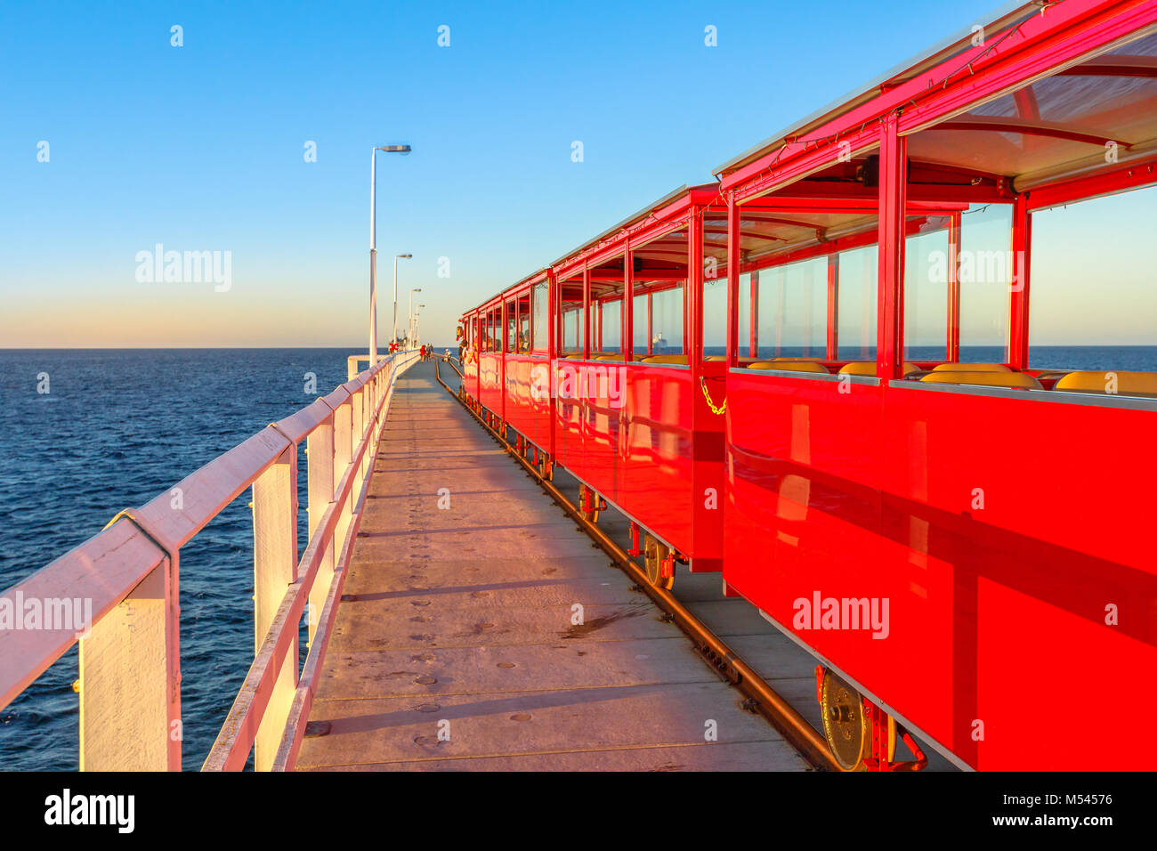 Perspektivische Ansicht von Vintage red elektrische Zug am Jetty Busselton Titel in Busselton, Western Australia. Berühmte Ort bei Sonnenuntergang. Busselton Jetty ist die längste hölzerne Seebrücke in der Welt. Stockfoto