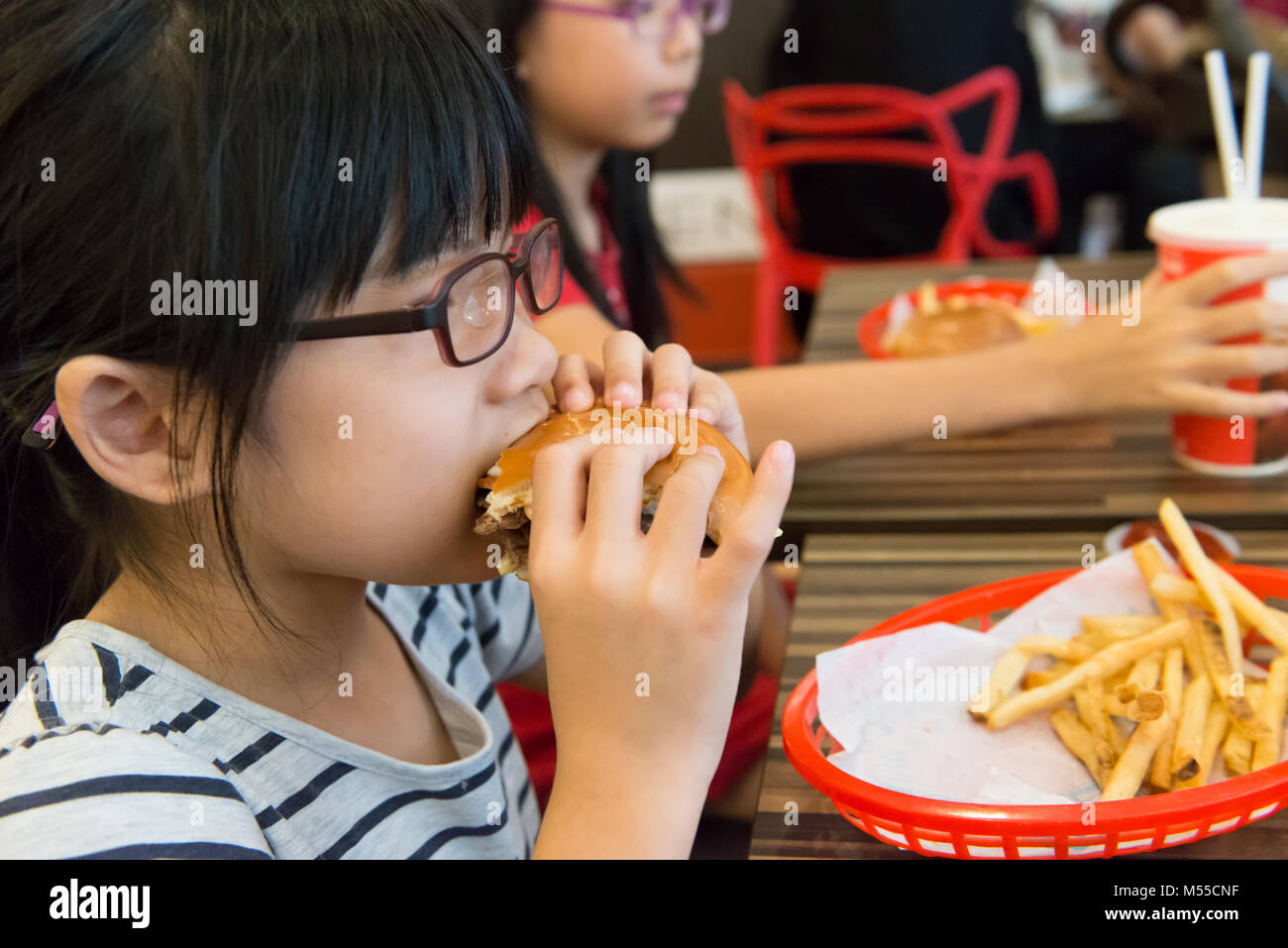 Asiatische Kind isst einen Hamburger und Pommes Frites Stockfoto