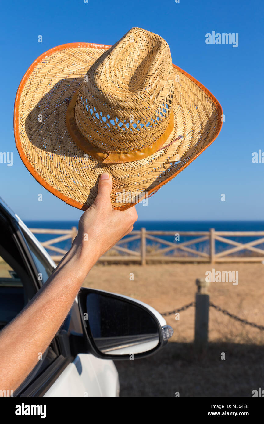 Arm im Auto Holding straw hat an der Küste Stockfoto