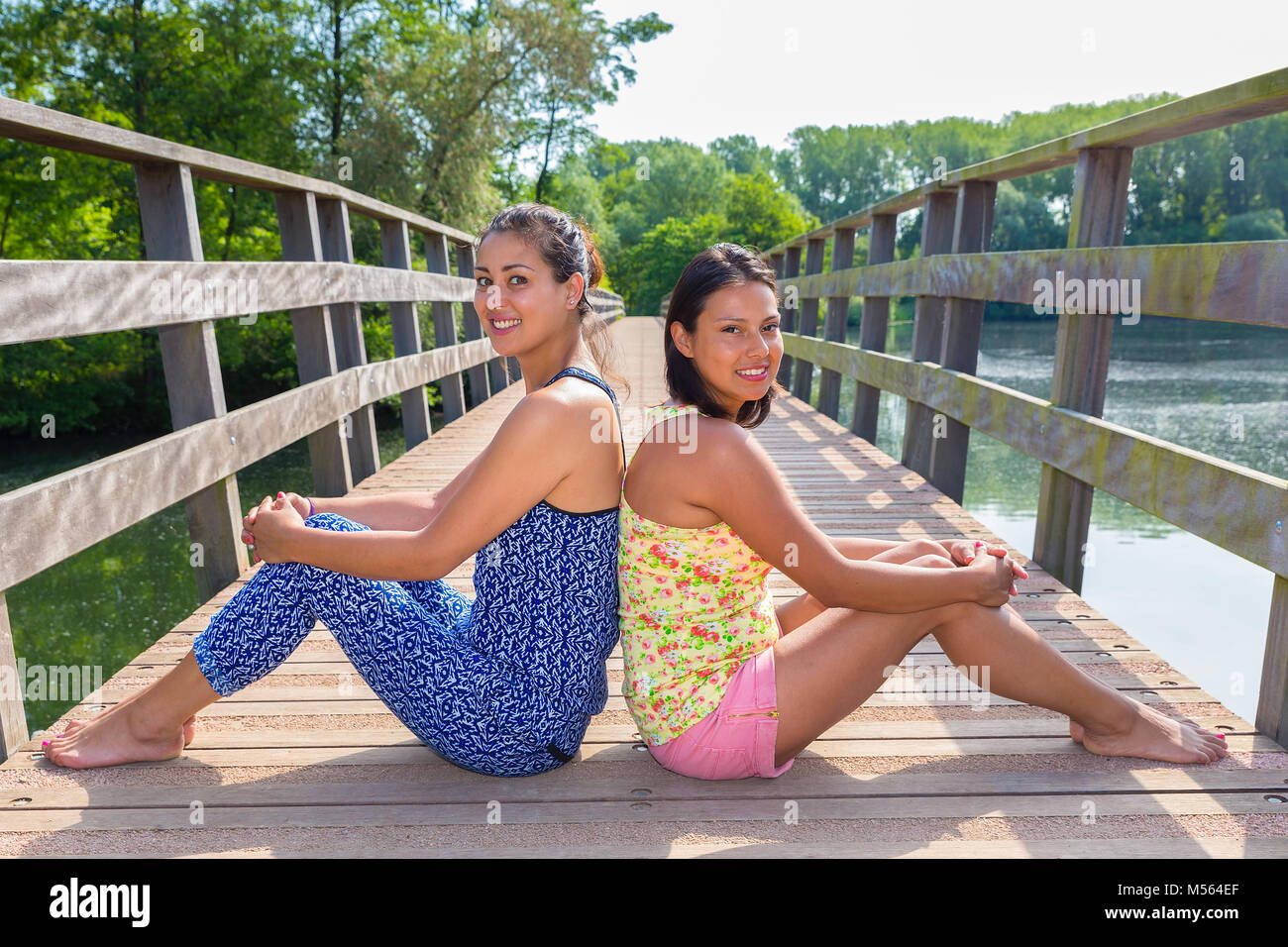 Zwei Freunde sitzen zusammen auf hölzerne Brücke in der Natur Stockfoto