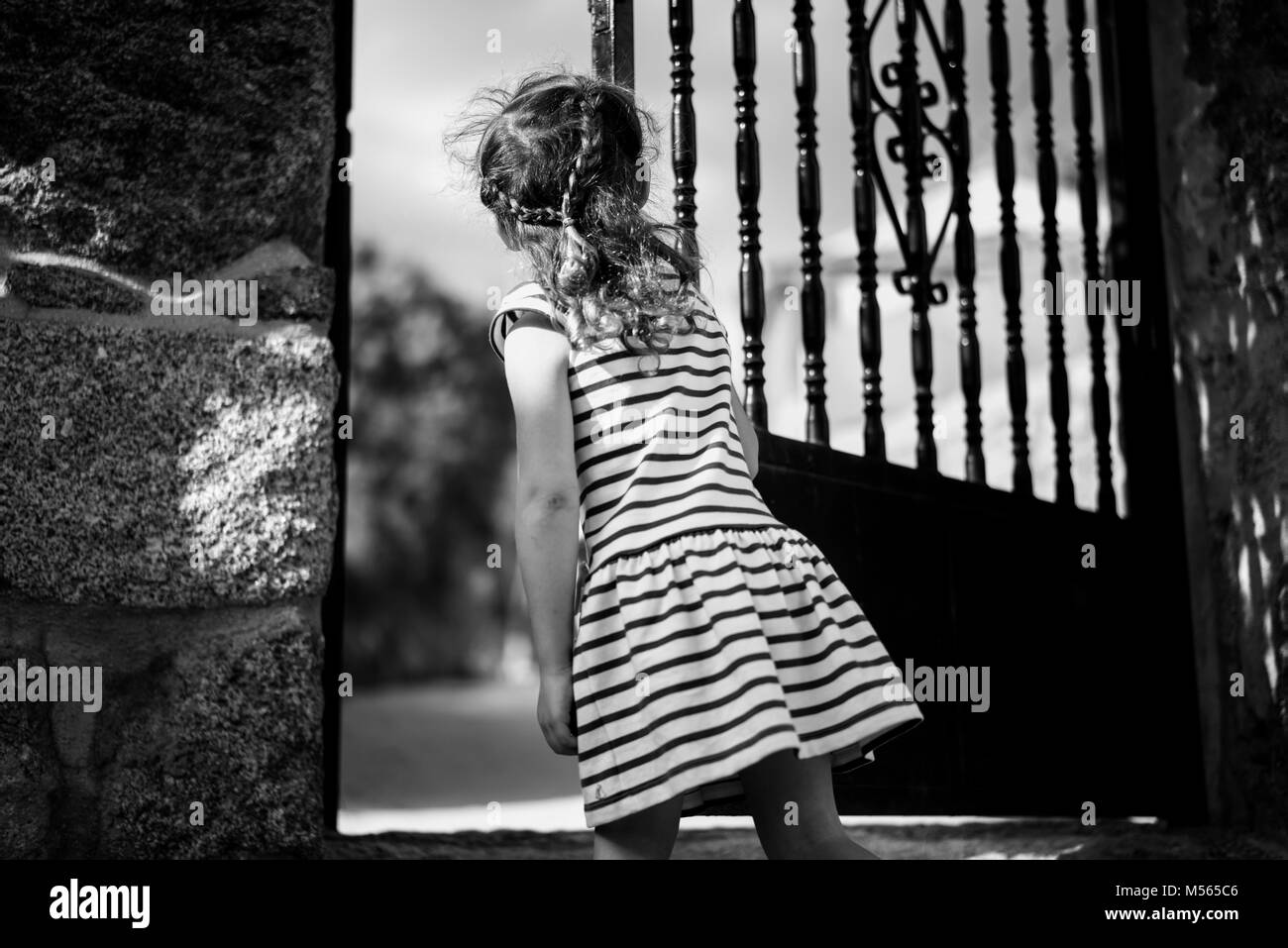 Kleines Mädchen eine Tür geöffnet, einige Geheimnis erwartet… Bild einer blonden, lockigen Haaren Kind. Stockfoto