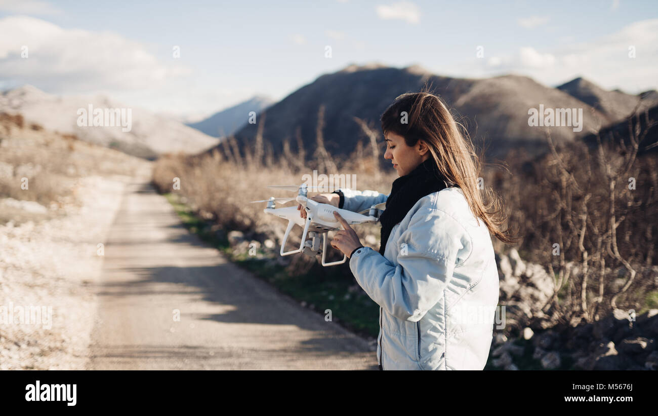 Junge Frau videographer Fang fliegen Flugzeuge mit Kamera. Kontrolle der Anlandung von Drone. Weibliche Filmemacher in der Natur mit Quad copter Flugzeuge an Ca Stockfoto